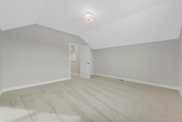 additional living space featuring vaulted ceiling and light carpet