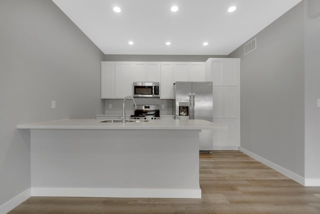 kitchen with stainless steel appliances, sink, light hardwood / wood-style flooring, and white cabinets