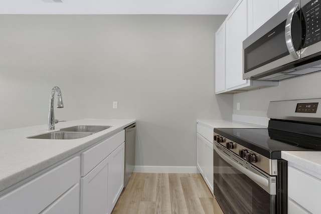 kitchen with white cabinetry, sink, stainless steel appliances, and light wood-type flooring