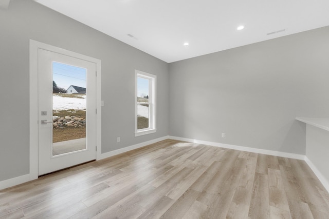 spare room with a wealth of natural light and light hardwood / wood-style floors