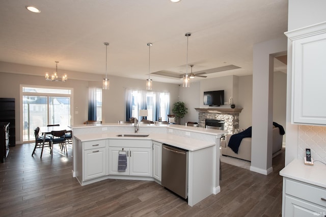 kitchen featuring a stone fireplace, dishwasher, sink, and white cabinets