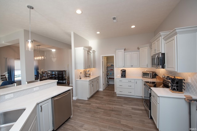 kitchen featuring hanging light fixtures, backsplash, stainless steel appliances, and white cabinets