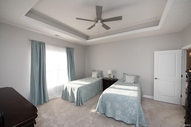 carpeted bedroom with a tray ceiling and ceiling fan