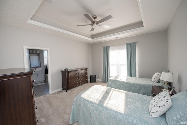 bedroom with ceiling fan, connected bathroom, a raised ceiling, and light carpet