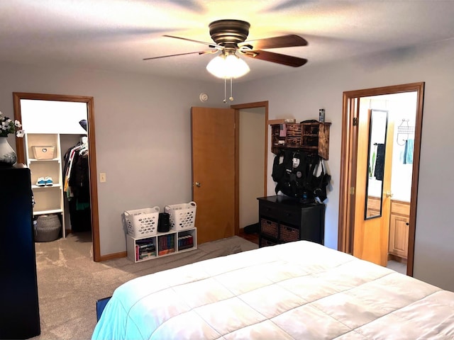 carpeted bedroom with connected bathroom, a spacious closet, a closet, and ceiling fan