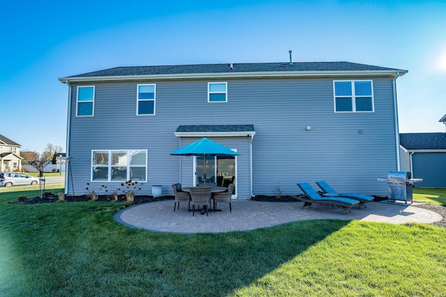 rear view of house featuring a lawn and a patio