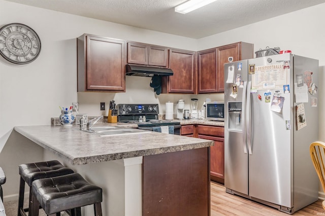 kitchen with sink, a breakfast bar, stainless steel appliances, kitchen peninsula, and light wood-type flooring