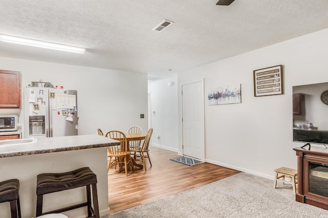 kitchen featuring refrigerator with ice dispenser, hardwood / wood-style flooring, and a textured ceiling