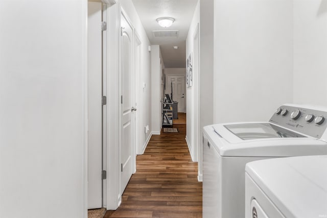 clothes washing area featuring dark hardwood / wood-style floors and washer and clothes dryer