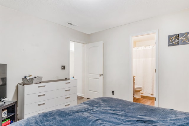 bedroom with connected bathroom and light wood-type flooring