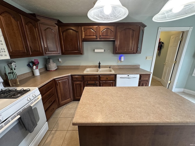 kitchen with hanging light fixtures, sink, light tile patterned floors, and white appliances