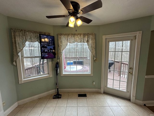 doorway featuring light tile patterned flooring, plenty of natural light, ceiling fan, and a textured ceiling