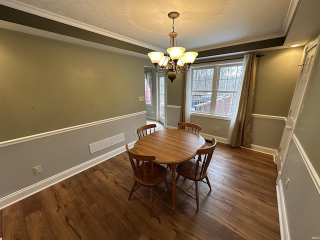 dining area featuring a textured ceiling, ornamental molding, dark hardwood / wood-style floors, and a chandelier