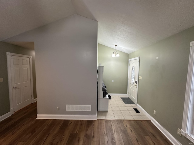 entryway with lofted ceiling, light hardwood / wood-style floors, and a textured ceiling