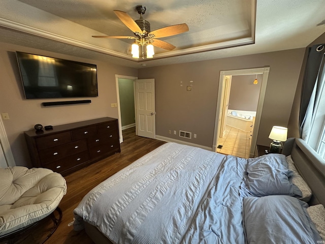 bedroom featuring dark hardwood / wood-style flooring, a raised ceiling, ceiling fan, and ensuite bathroom