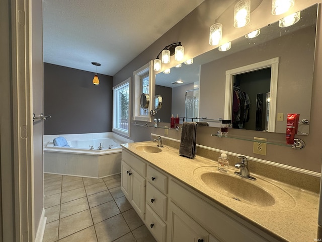 bathroom with tile patterned flooring, a bathing tub, vanity, and a textured ceiling