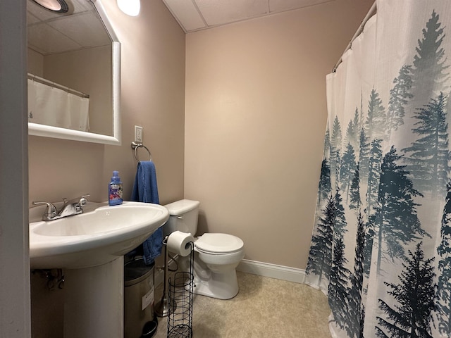 bathroom featuring a paneled ceiling, toilet, and sink