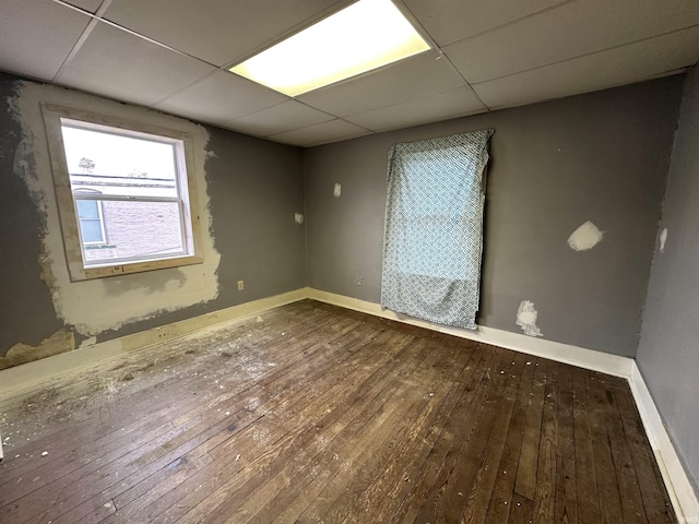 empty room featuring wood-type flooring and a drop ceiling