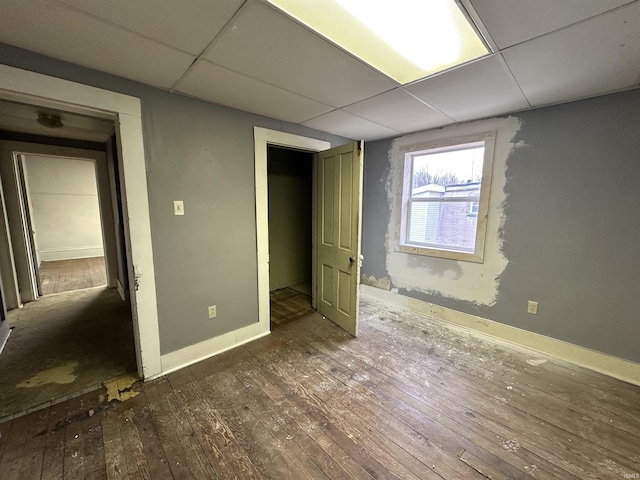 unfurnished bedroom featuring dark hardwood / wood-style floors and a drop ceiling