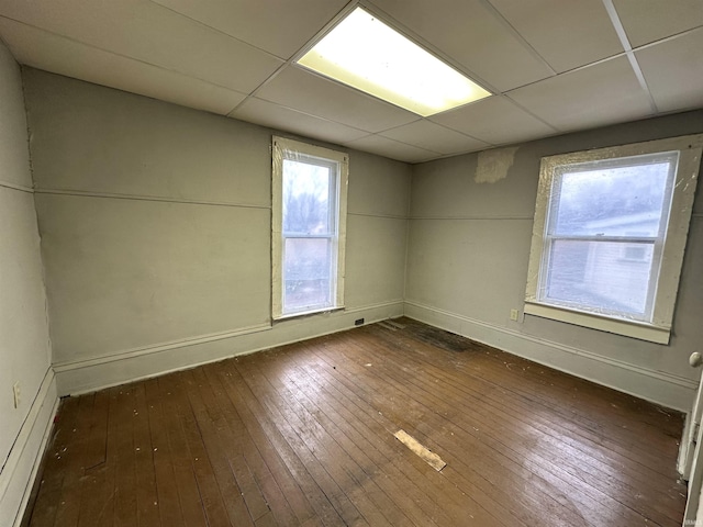 spare room featuring dark hardwood / wood-style floors and a drop ceiling