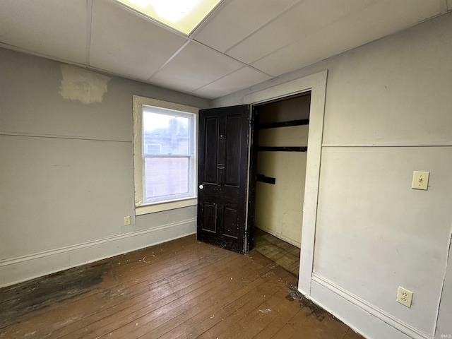 unfurnished bedroom featuring dark hardwood / wood-style flooring, a closet, and a drop ceiling