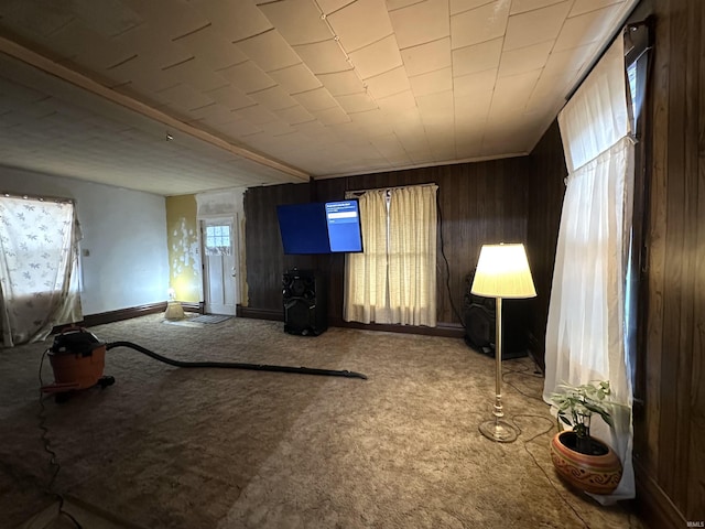 unfurnished living room featuring light colored carpet and wooden walls