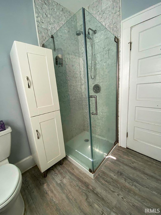 bathroom with an enclosed shower, hardwood / wood-style floors, and toilet