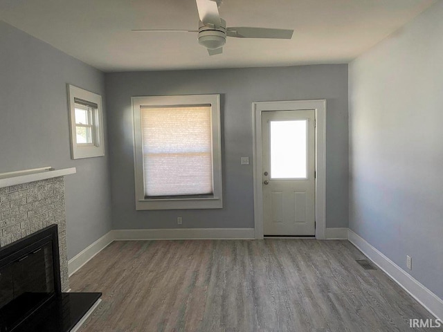 doorway to outside featuring light hardwood / wood-style flooring, a fireplace, and ceiling fan