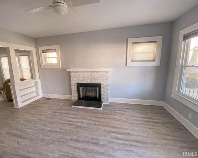 unfurnished living room featuring hardwood / wood-style floors, a brick fireplace, and a wealth of natural light