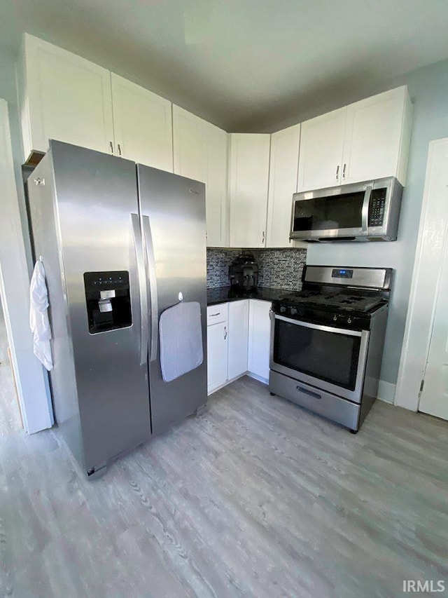 kitchen featuring backsplash, light hardwood / wood-style flooring, white cabinets, and appliances with stainless steel finishes