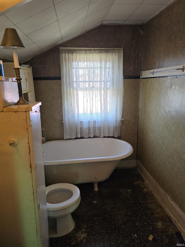 bathroom with a bath, vaulted ceiling, and toilet