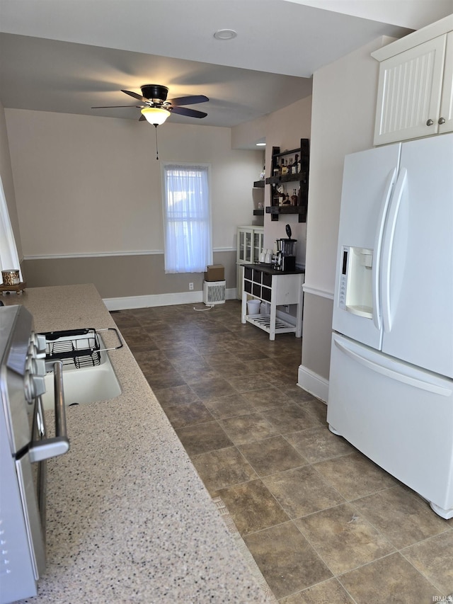 kitchen with ceiling fan, white refrigerator with ice dispenser, white cabinets, and light stone counters