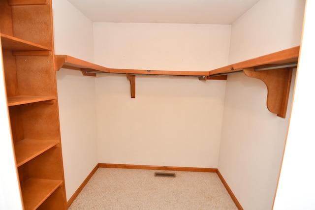 walk in closet featuring light colored carpet