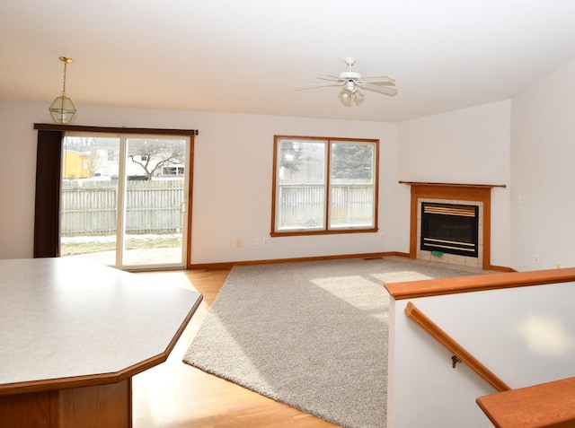 unfurnished living room with a tile fireplace, light wood-type flooring, and ceiling fan