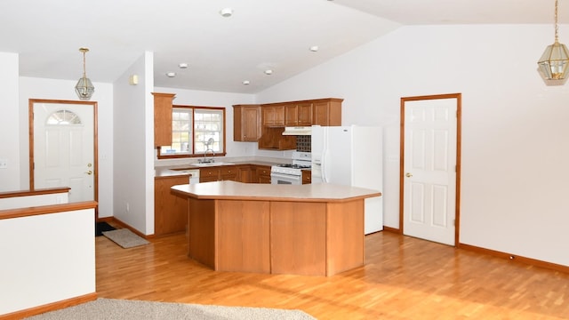 kitchen with white appliances, decorative light fixtures, sink, and a kitchen island