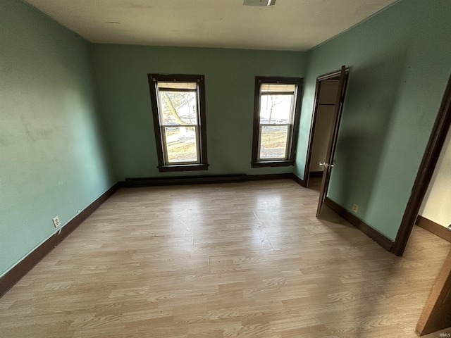 unfurnished room featuring light hardwood / wood-style floors and a baseboard heating unit