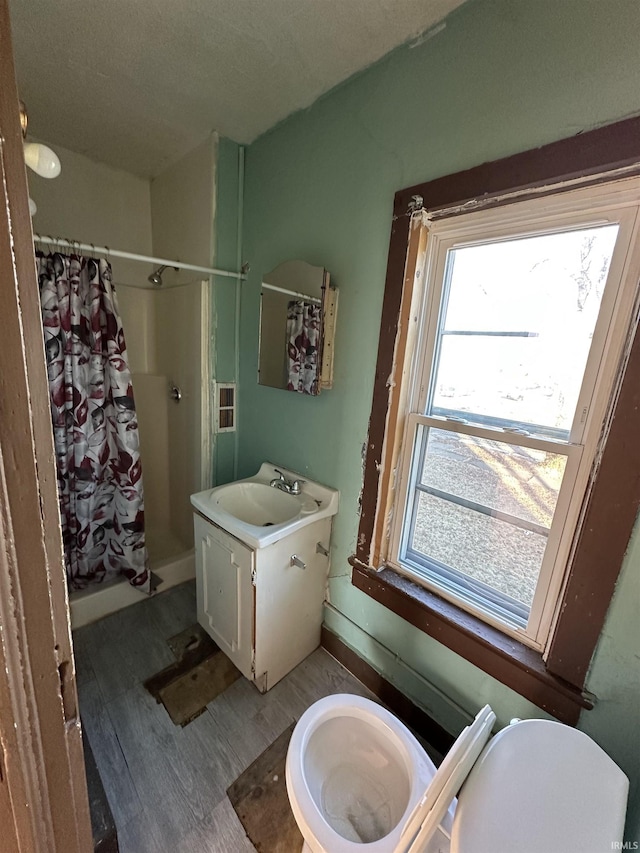 bathroom with walk in shower, vanity, toilet, and hardwood / wood-style floors