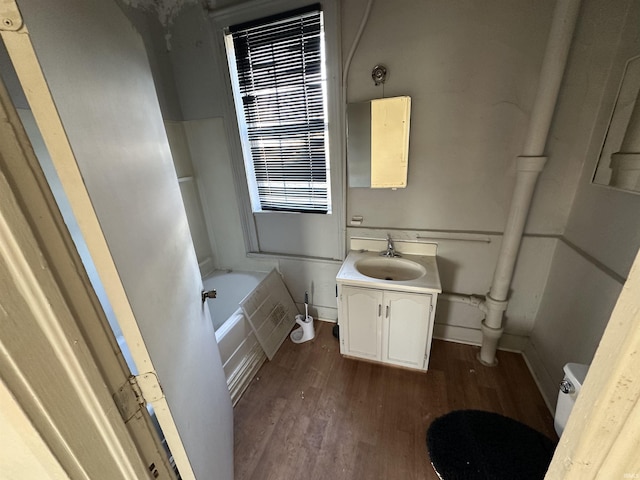 bathroom with hardwood / wood-style flooring, vanity, a bathtub, and toilet