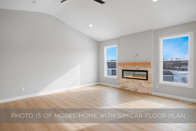 unfurnished living room with vaulted ceiling, ceiling fan, a fireplace, and light wood-type flooring