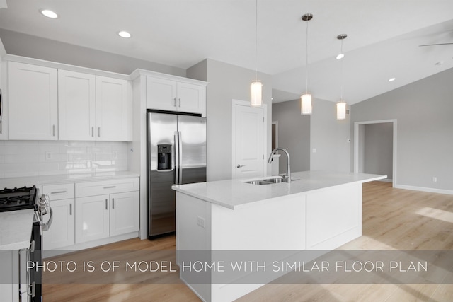 kitchen with white cabinetry, appliances with stainless steel finishes, sink, and a center island with sink