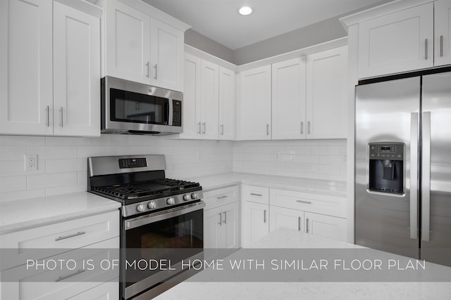 kitchen with white cabinetry, light stone countertops, decorative backsplash, and stainless steel appliances