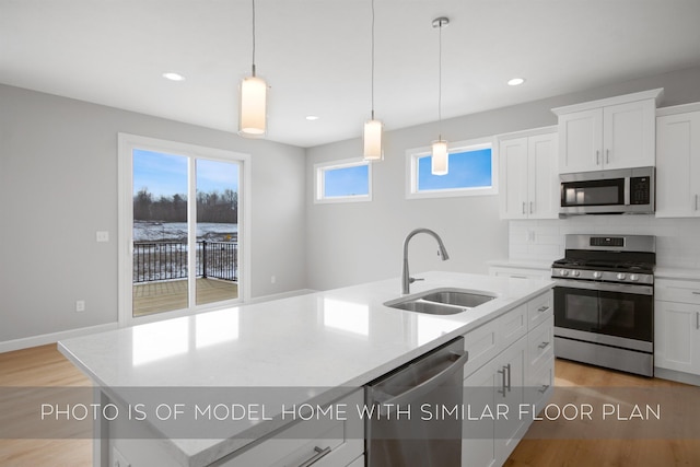 kitchen featuring sink, stainless steel appliances, white cabinets, and a center island with sink