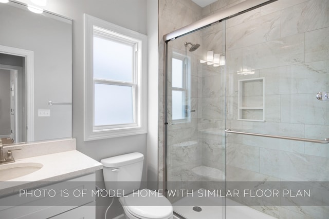 bathroom featuring vanity, a shower with shower door, and toilet