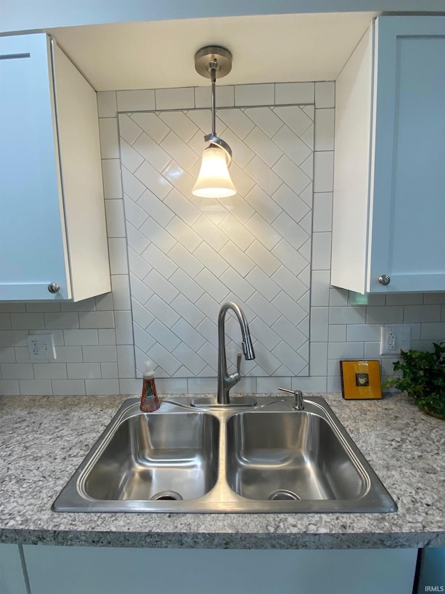 kitchen featuring sink, pendant lighting, white cabinets, and decorative backsplash