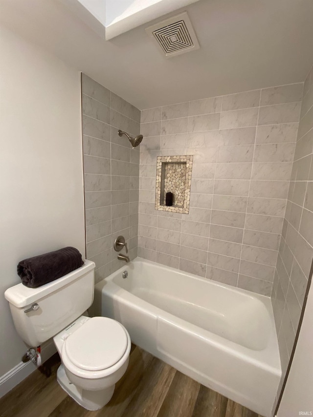 bathroom with tiled shower / bath, wood-type flooring, and toilet