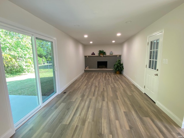 unfurnished living room featuring dark hardwood / wood-style flooring and a brick fireplace