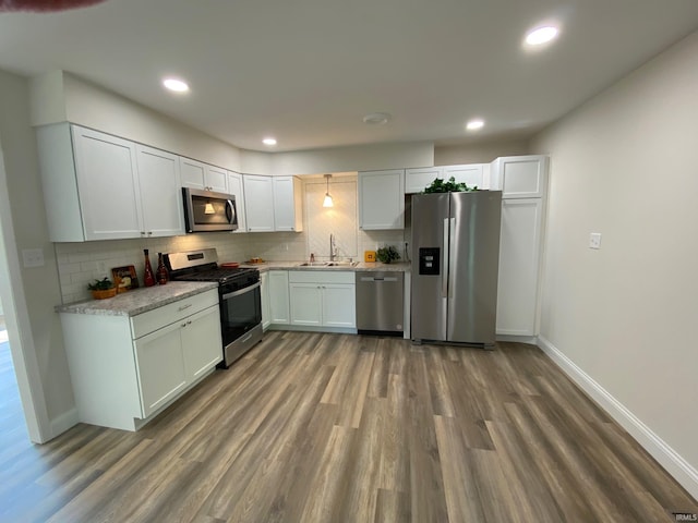 kitchen featuring sink, appliances with stainless steel finishes, dark hardwood / wood-style flooring, decorative backsplash, and white cabinets