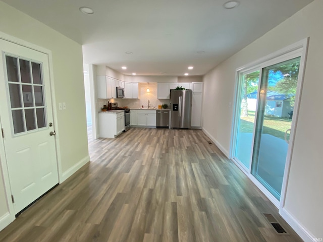 kitchen featuring sink, white cabinetry, appliances with stainless steel finishes, dark hardwood / wood-style floors, and decorative backsplash