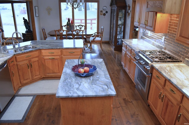 kitchen featuring sink, dark wood-type flooring, appliances with stainless steel finishes, light stone counters, and a kitchen island