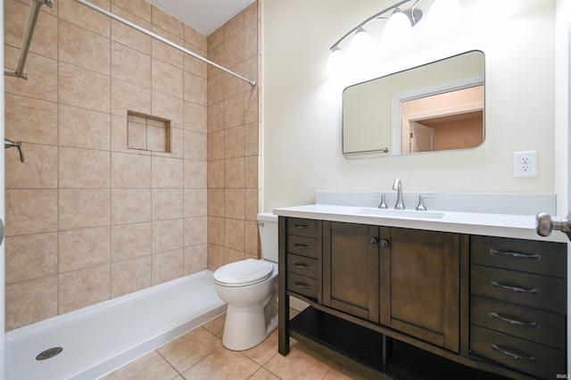 bathroom featuring tile patterned flooring, vanity, toilet, and a tile shower